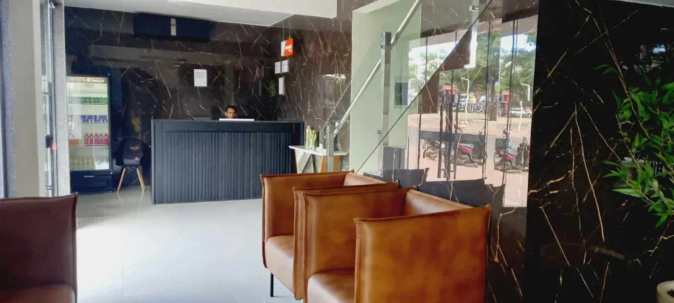 Um lobby de hotel com balcão de recepção e cadeiras.