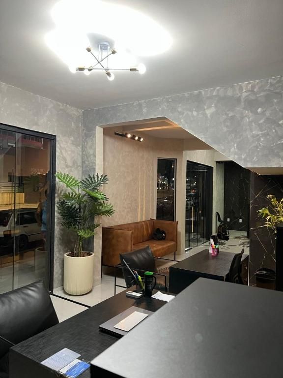 Uma sala de estar com um sofá, escrivaninha, cadeiras e uma planta em vaso.