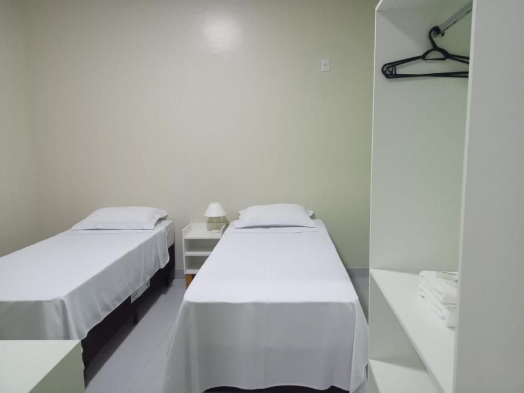 Um quarto com duas camas, uma mesa de cabeceira e um armário.