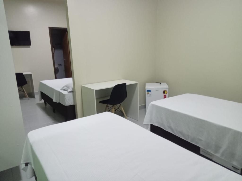 Um quarto de hotel com duas camas, uma escrivaninha e uma televisão.