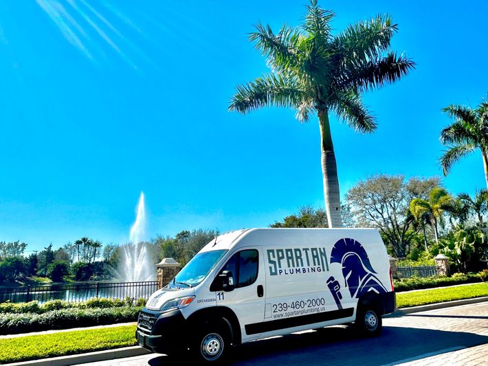 A spartan van is parked on the side of the road next to a palm tree.