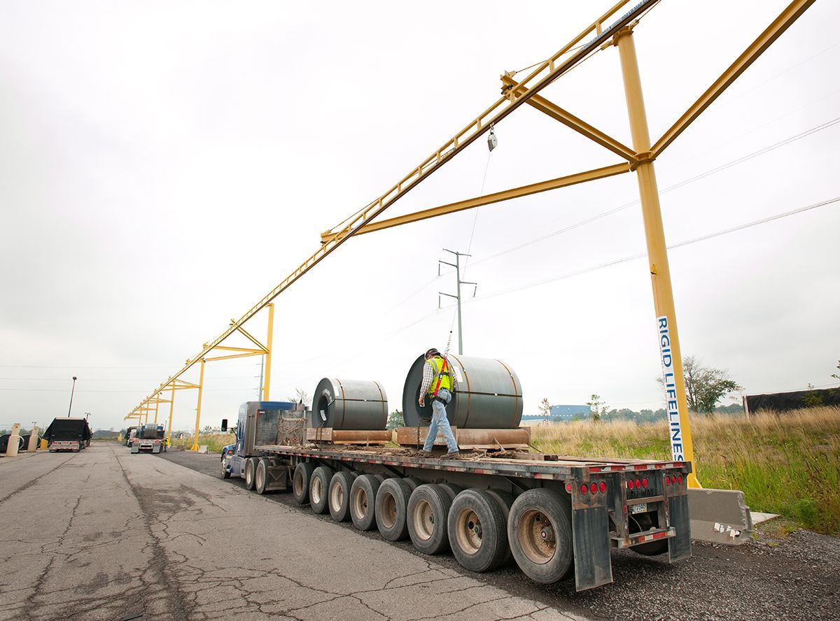 A truck is carrying large rolls of metal on a road