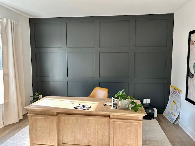 There is a desk in the middle of the room with a black wall behind it.