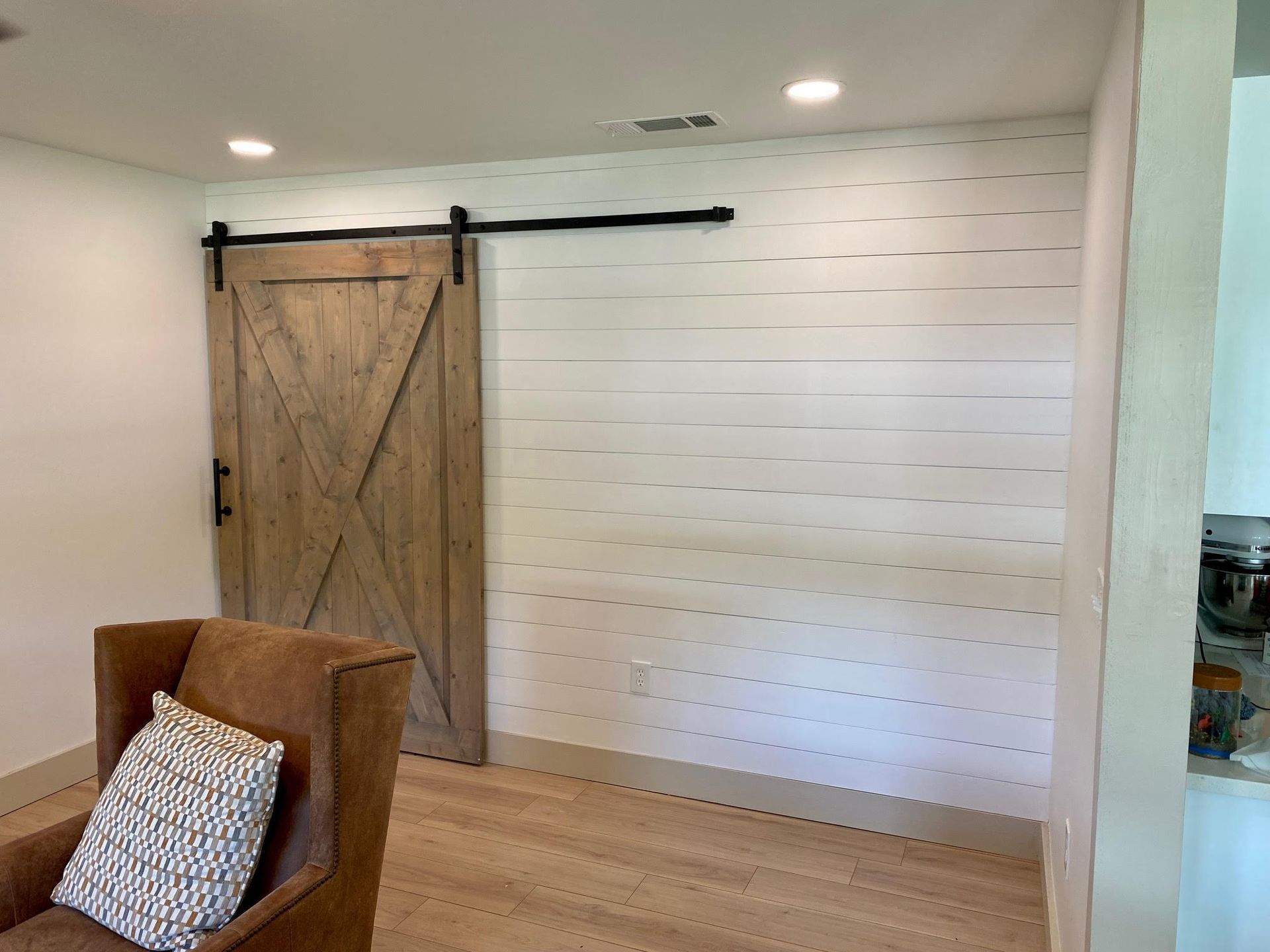 A living room with a sliding barn door and a chair.