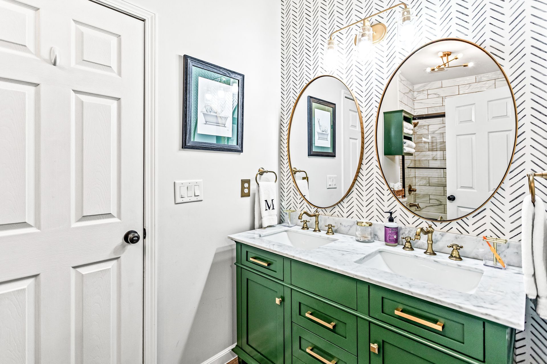 A bathroom with two sinks , two mirrors , and green cabinets.