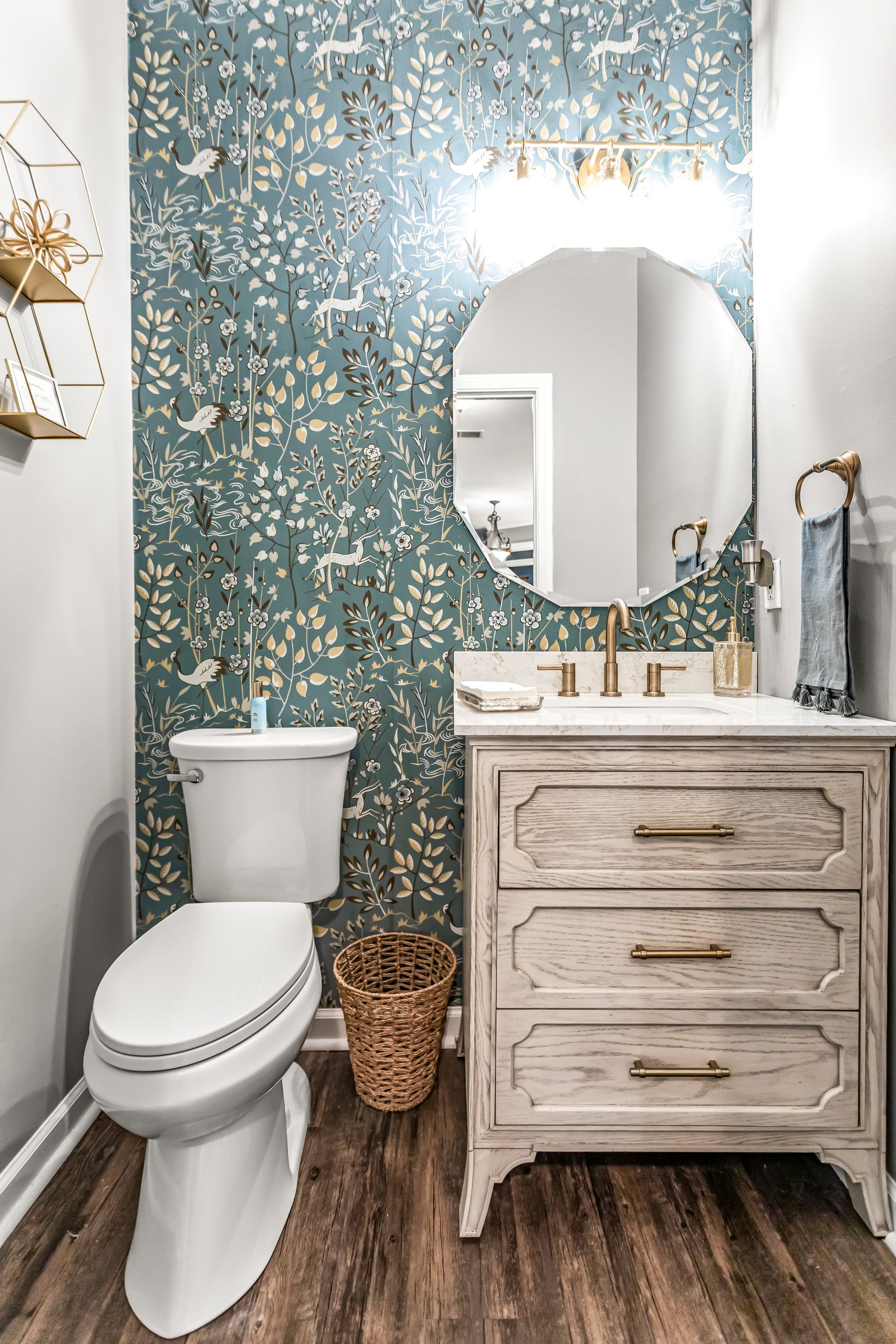 A bathroom with a toilet , sink , mirror and dresser.