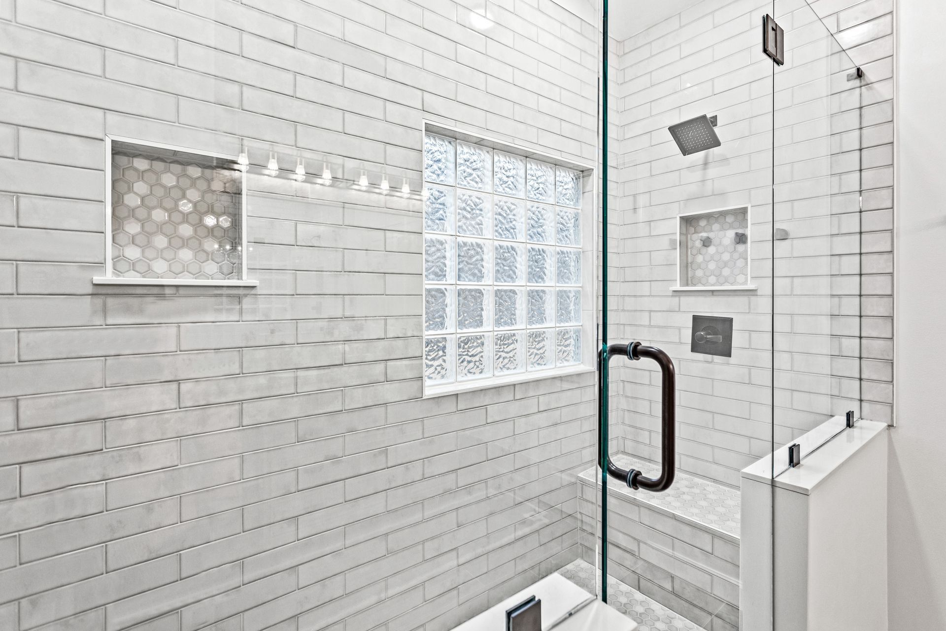 A bathroom with white brick walls and a glass shower door.