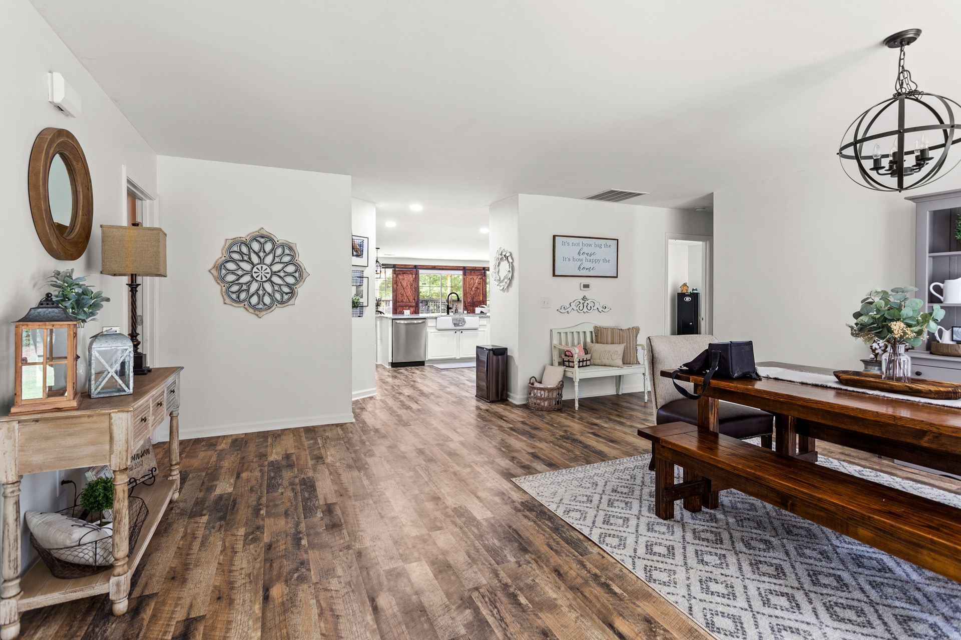 A living room with hardwood floors , a wooden table and benches.