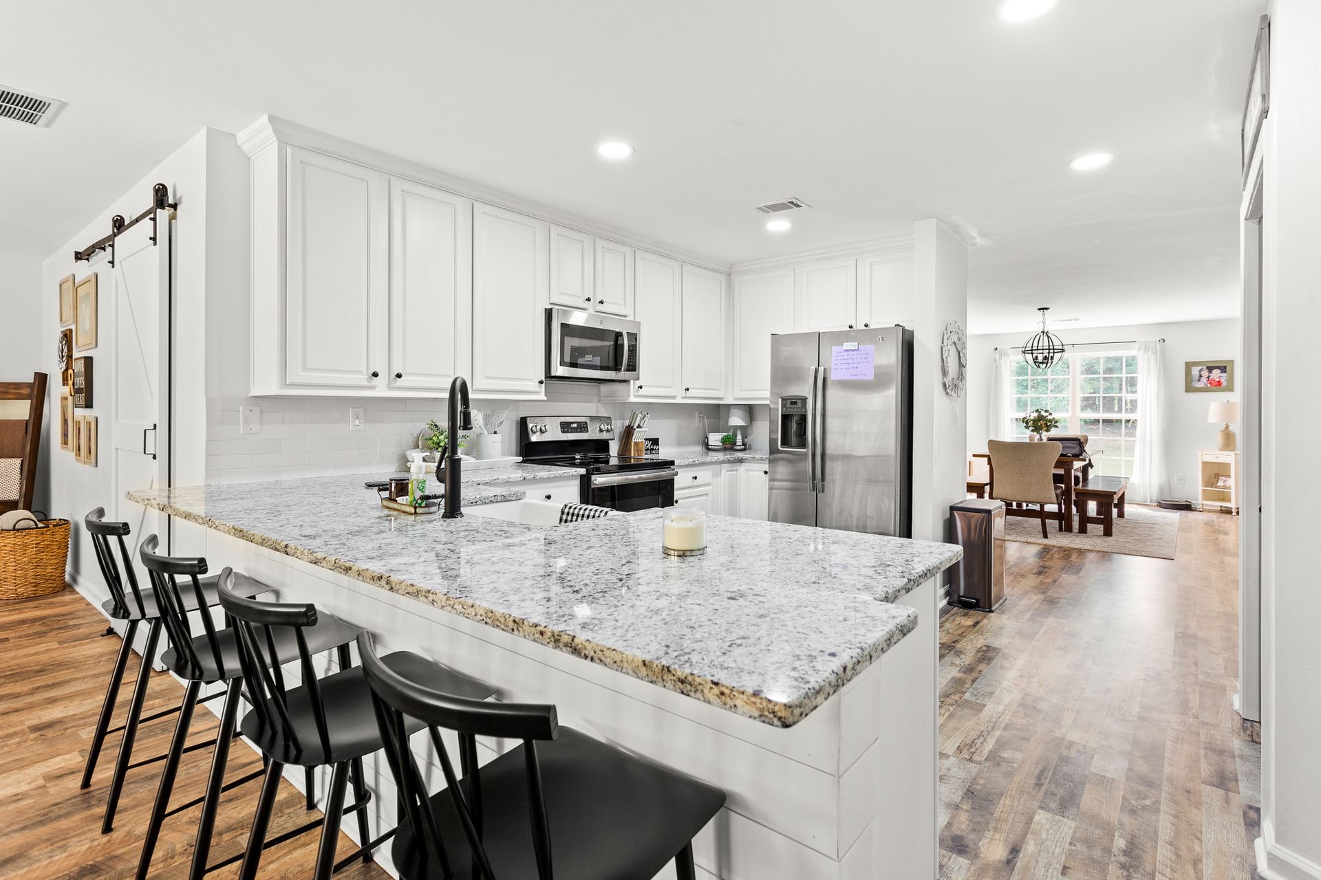 A kitchen with white cabinets , granite counter tops , stainless steel appliances and a large island.