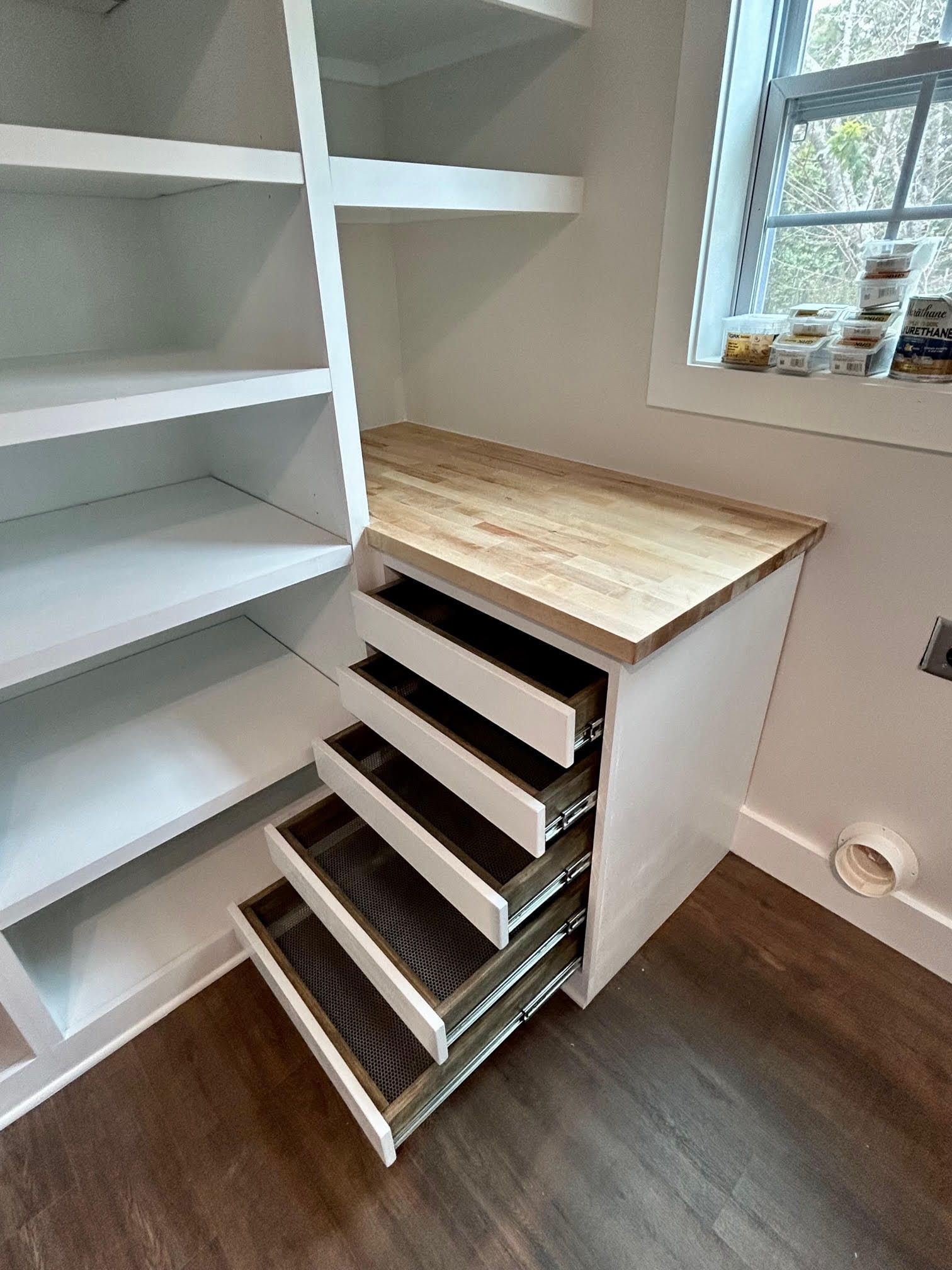 A room with shelves and drawers and a window.