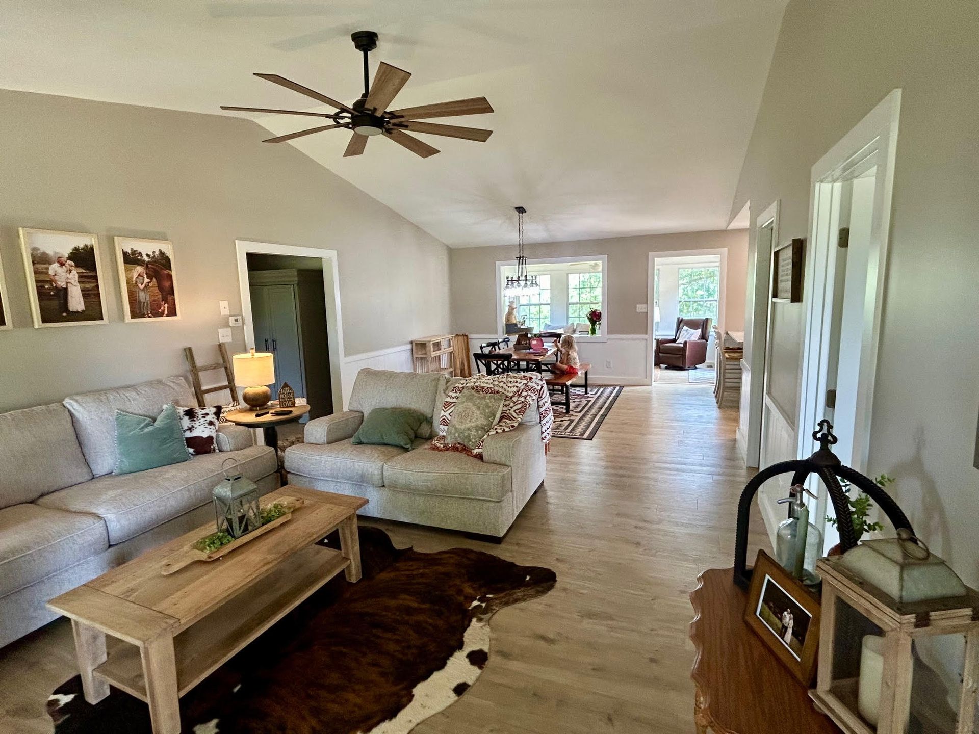 A living room with a couch , chair , coffee table and ceiling fan.