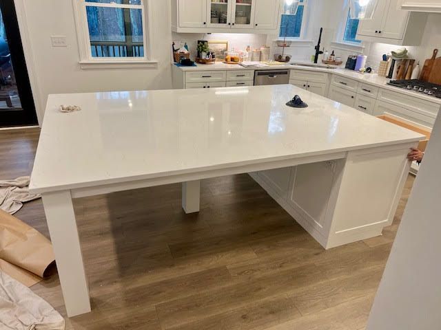 A kitchen with a large white table in the middle of it.