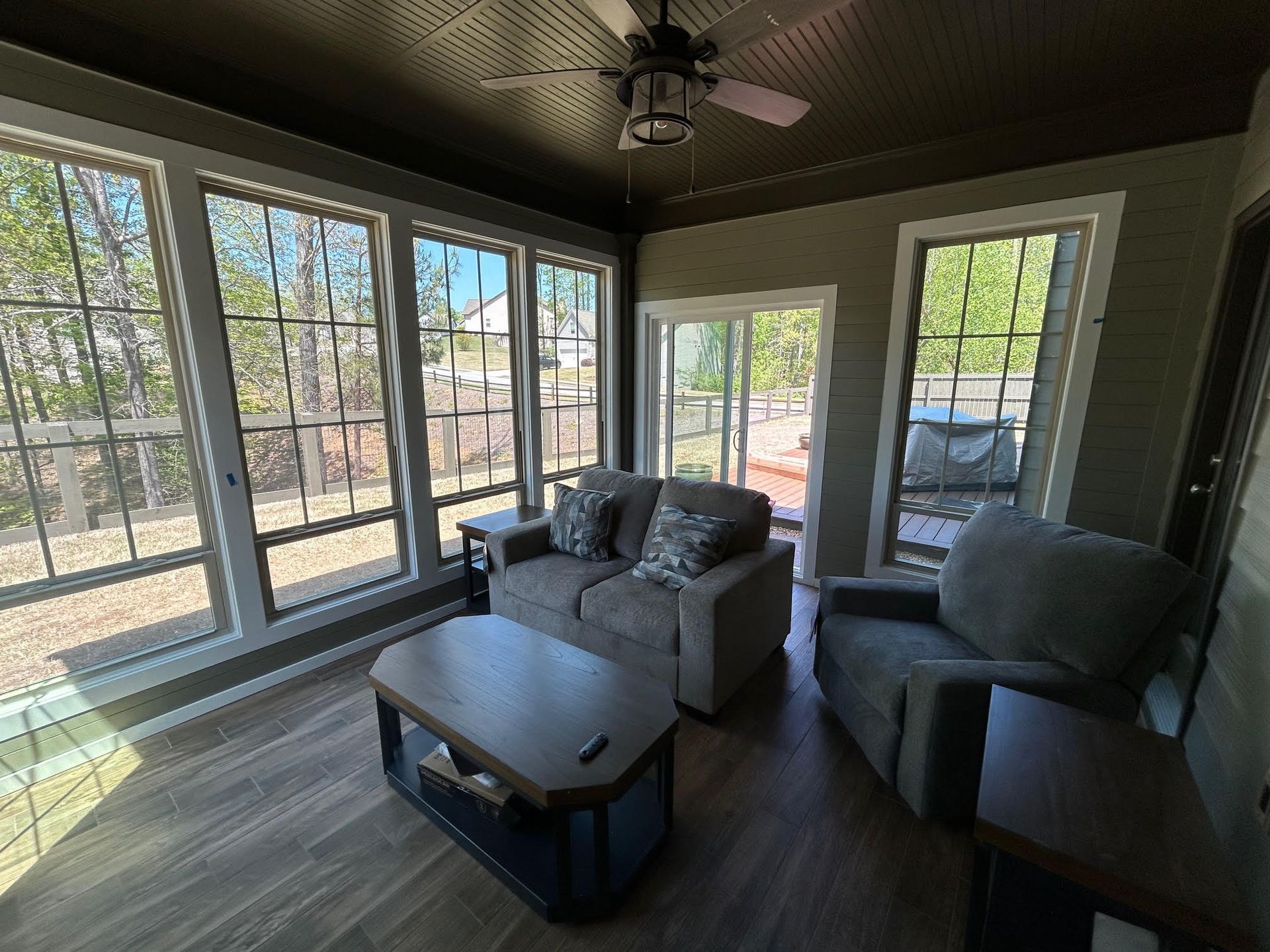 A living room with a couch , chair , coffee table and ceiling fan.