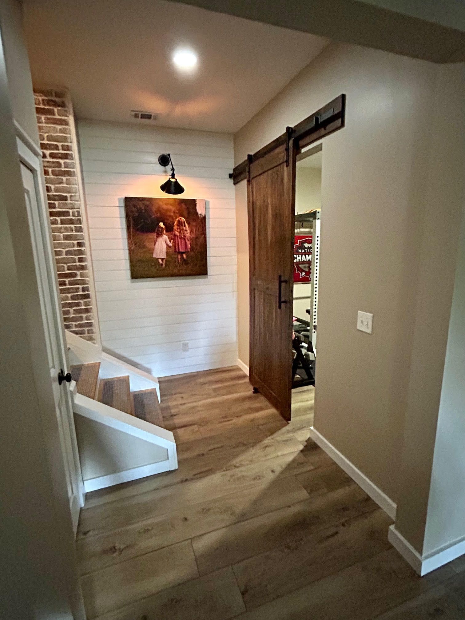 A hallway with a sliding barn door and stairs.