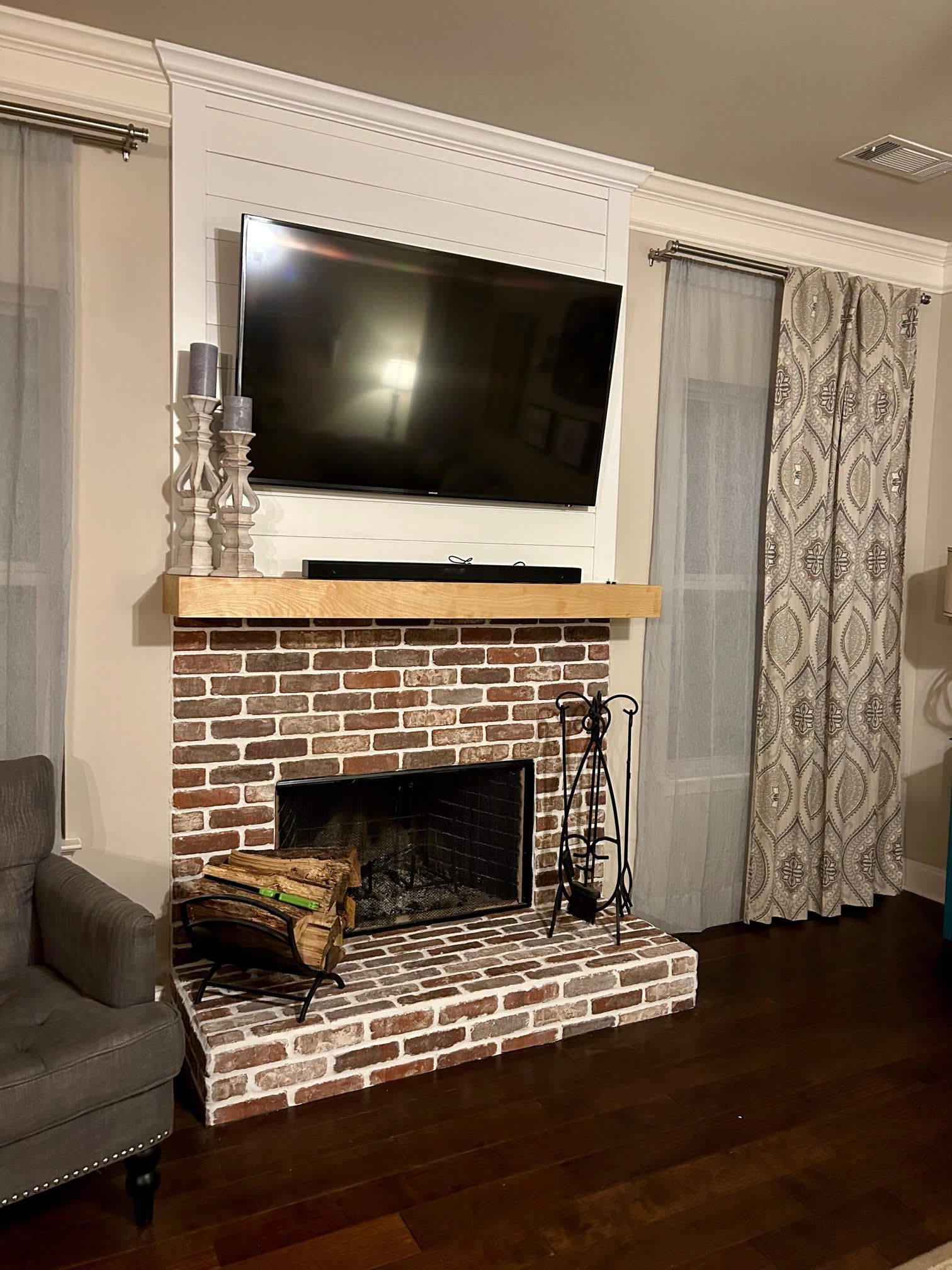 A living room with a brick fireplace and a flat screen tv.