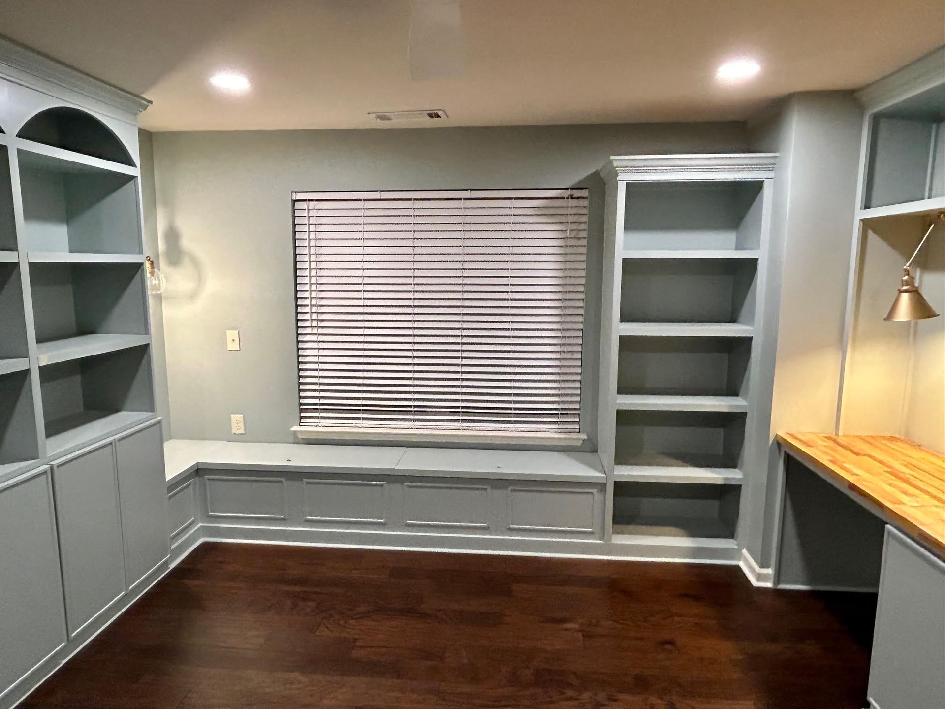A room with a window , shelves , and a desk.