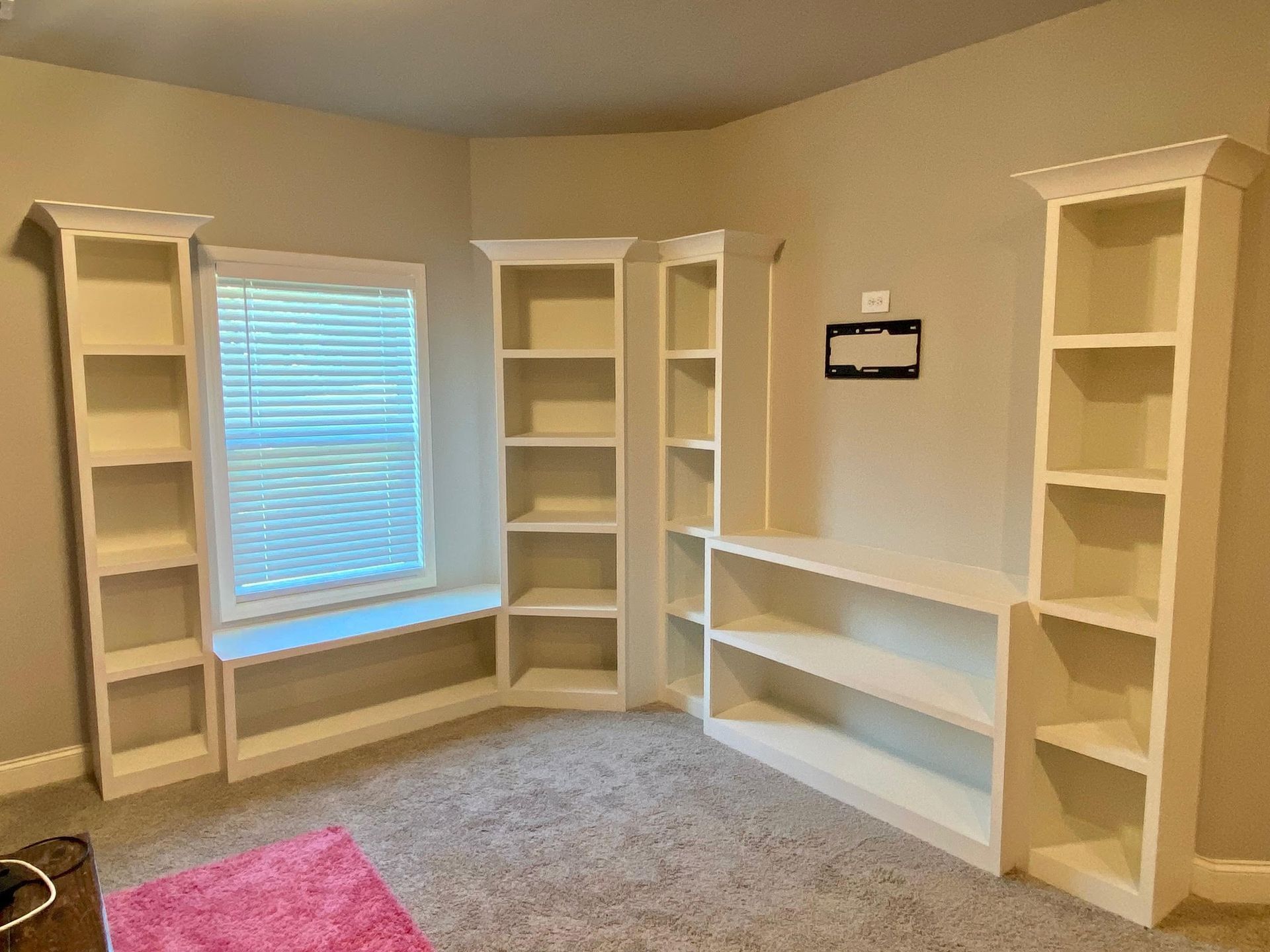 A room with a lot of shelves and a window.
