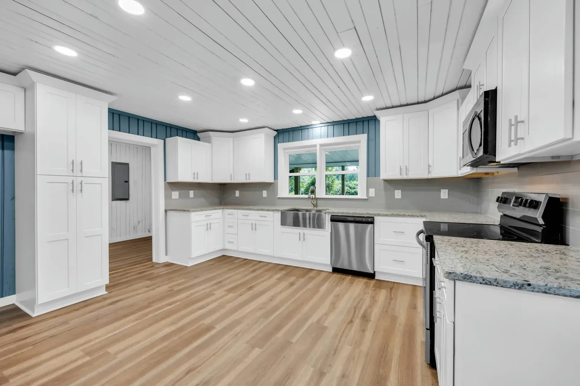 An empty kitchen with white cabinets and stainless steel appliances.