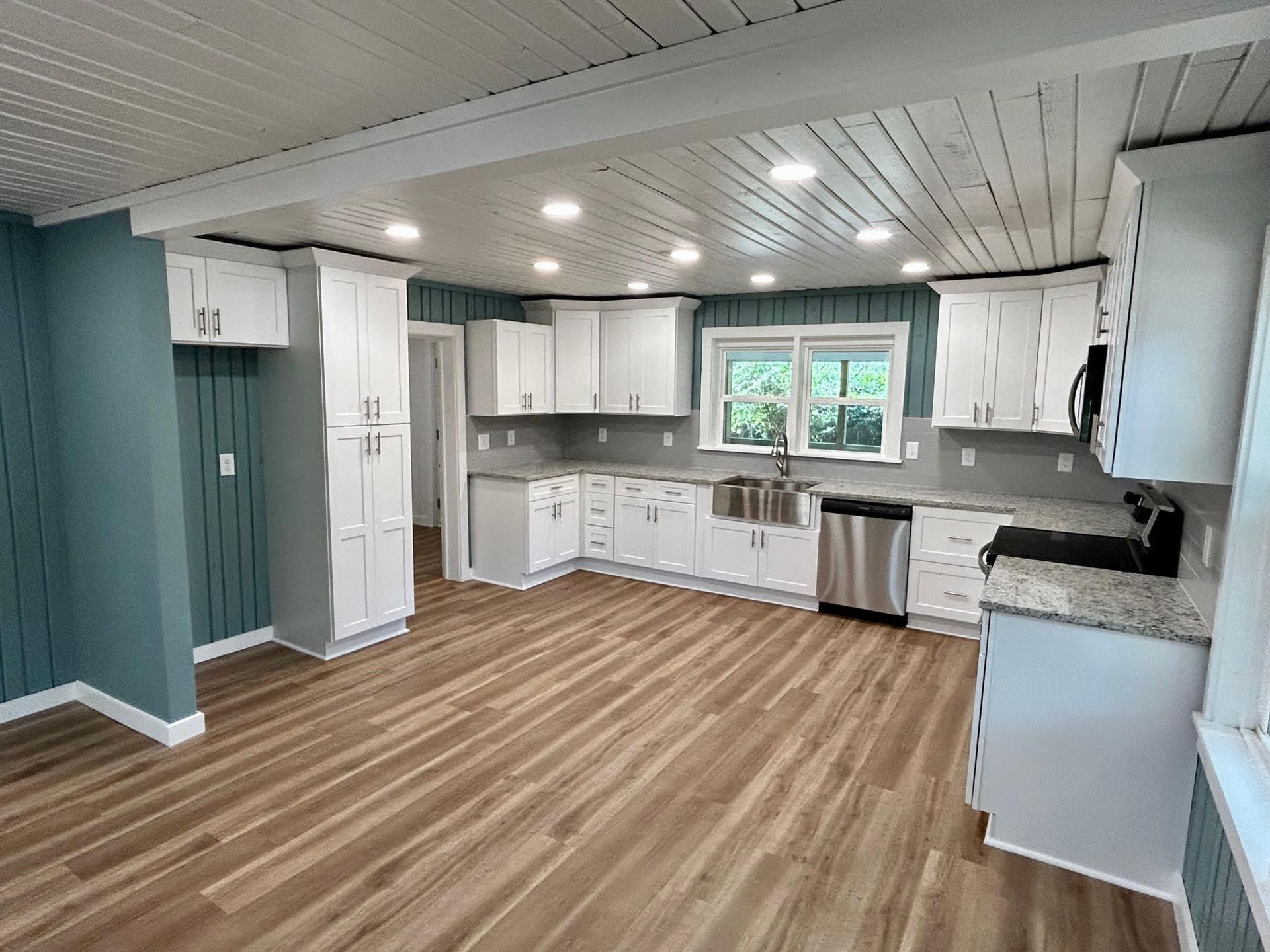 A kitchen with white cabinets , stainless steel appliances , and hardwood floors.