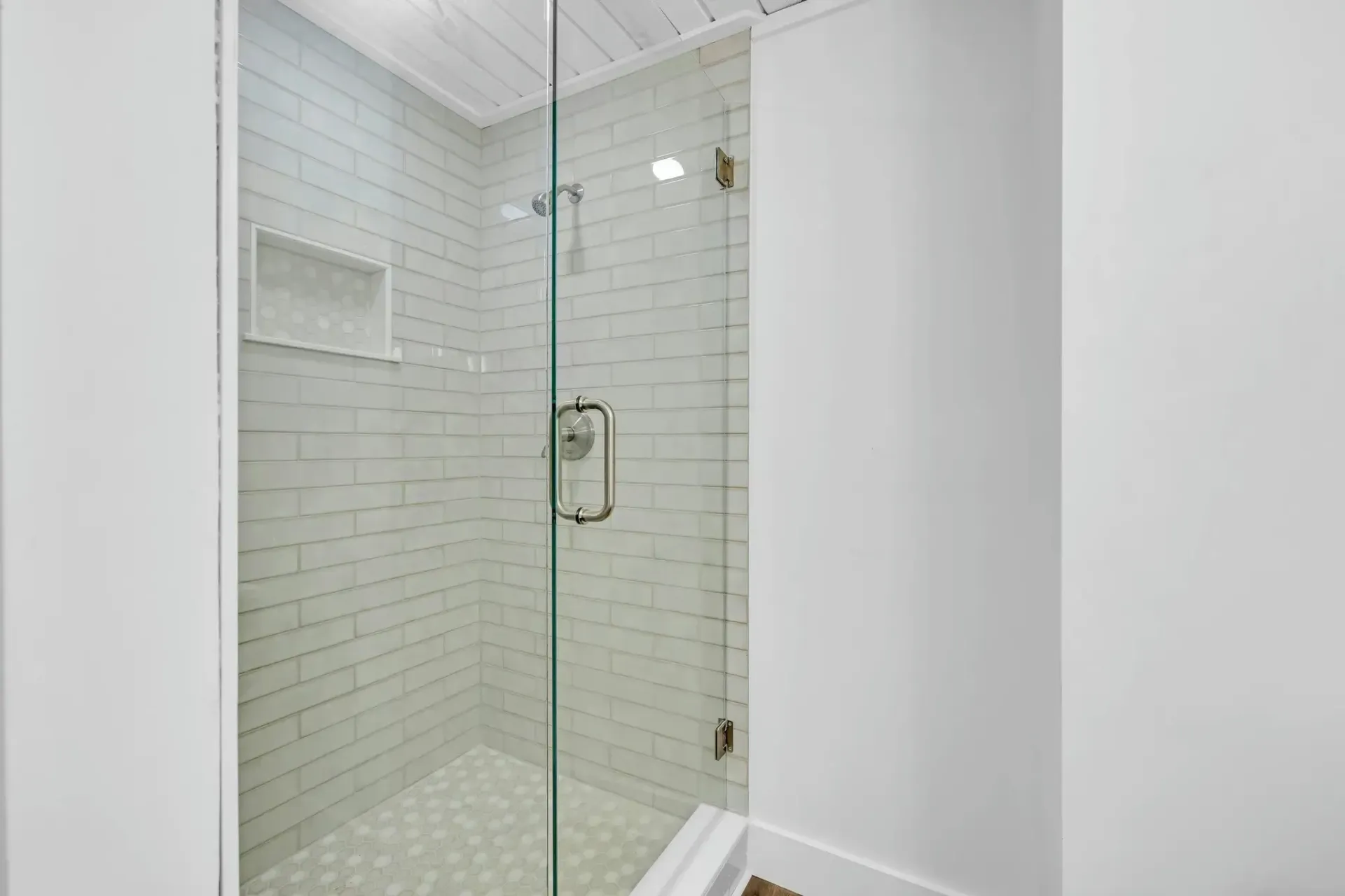 A bathroom with a walk in shower with a glass door.