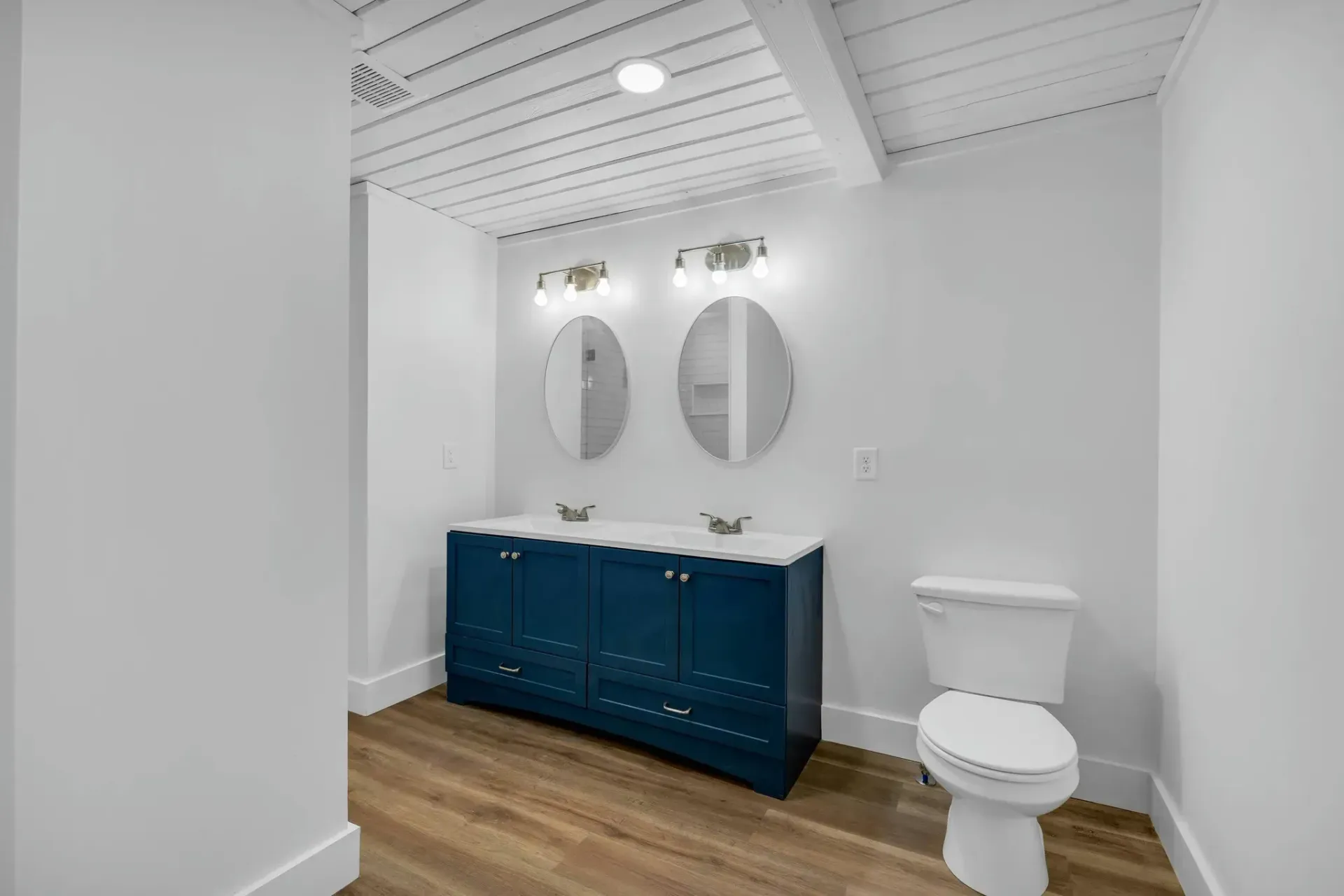 A bathroom with two sinks , a toilet and two mirrors.