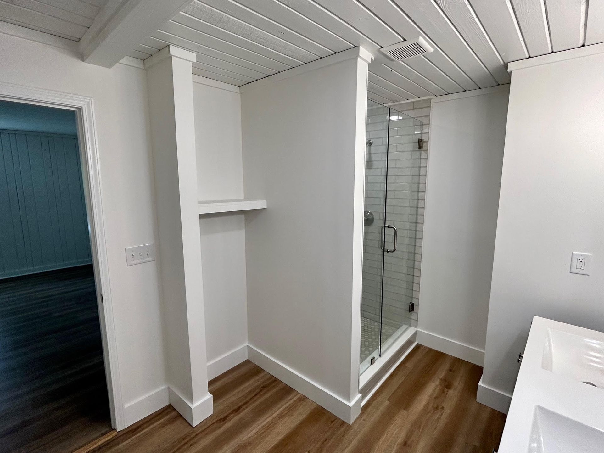 A bathroom with a walk in shower and a sink.