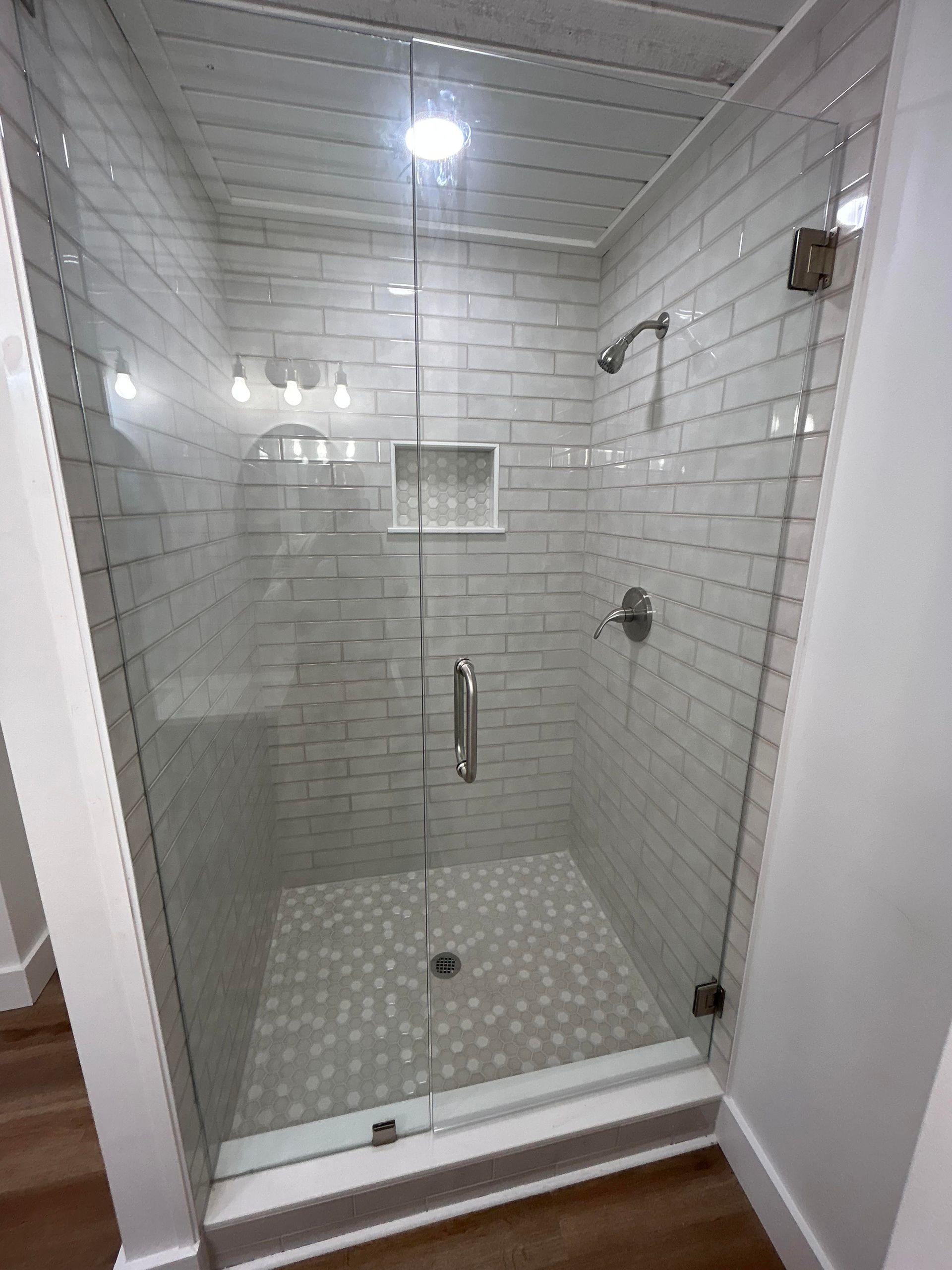 A bathroom with a walk in shower with a glass door.