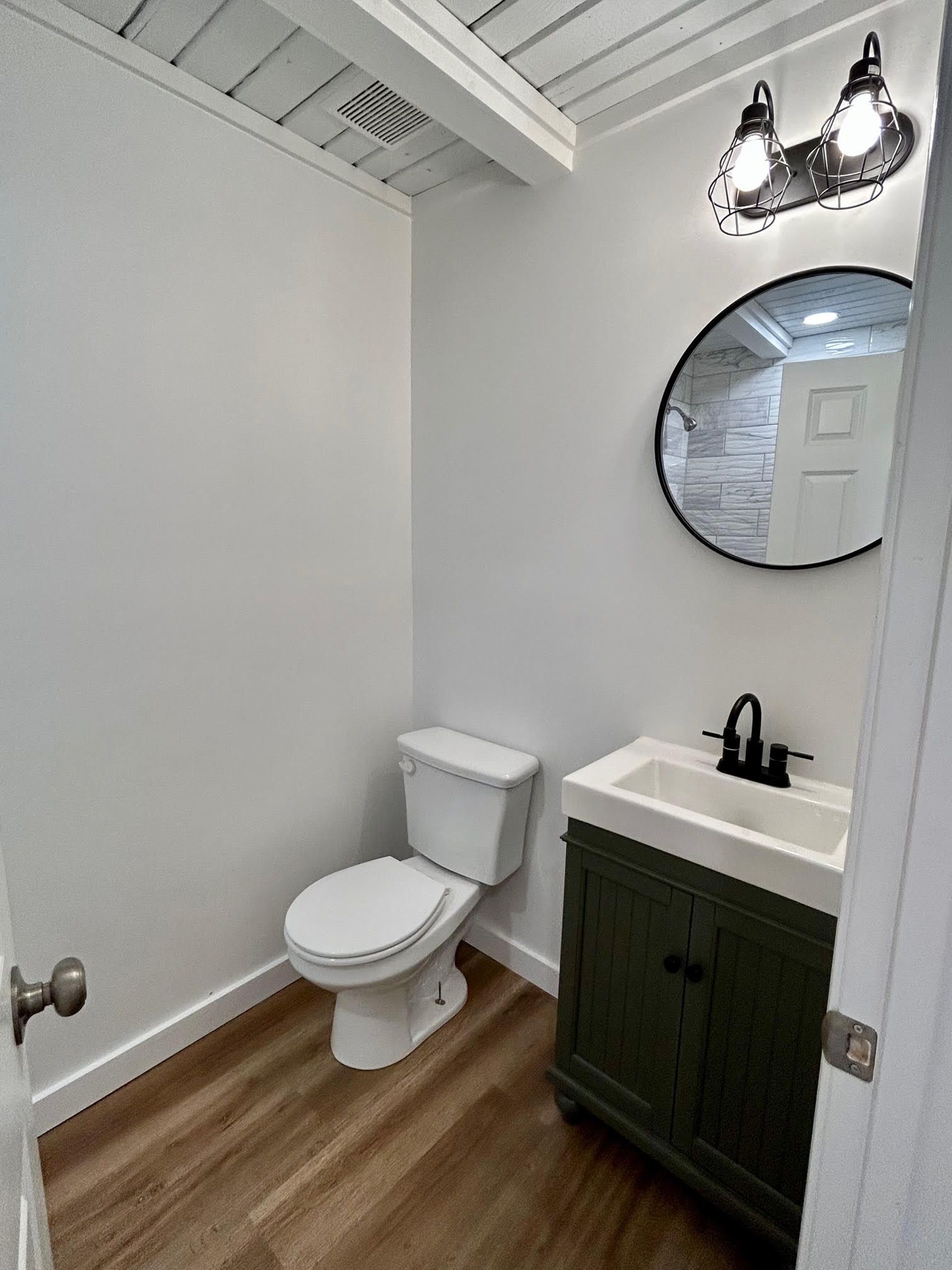 A bathroom with a toilet , sink and mirror.
