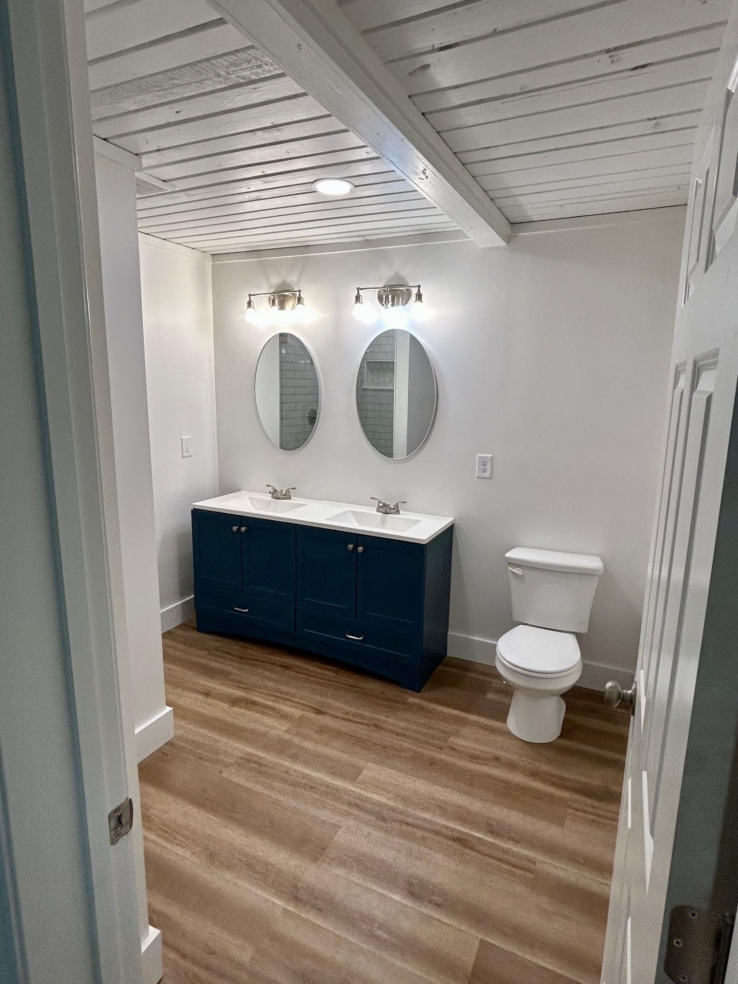 A bathroom with two sinks , a toilet and two mirrors.