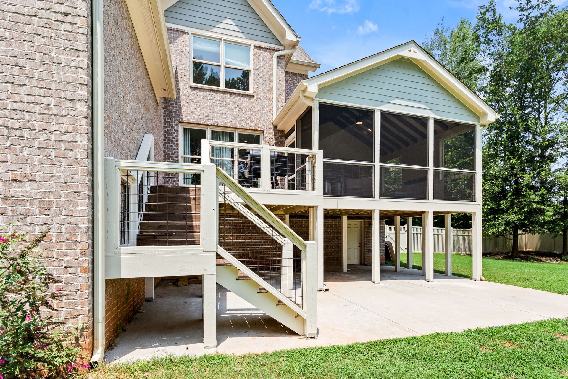 The back of a house with a screened in porch and stairs.