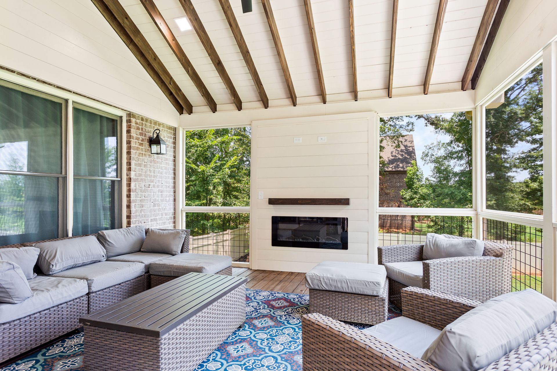 A screened in porch with furniture and a fireplace.