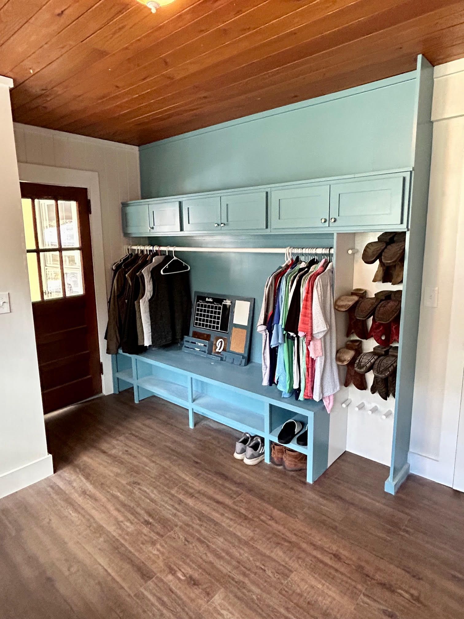A room with a closet and a bench filled with clothes and shoes.