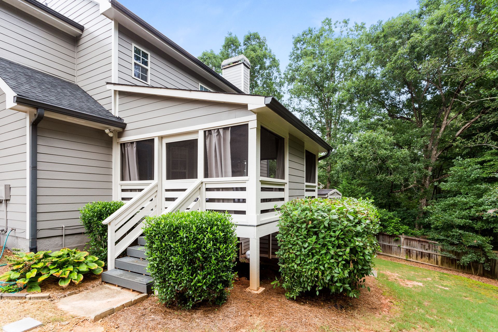 A house with a screened in porch and stairs leading up to it.