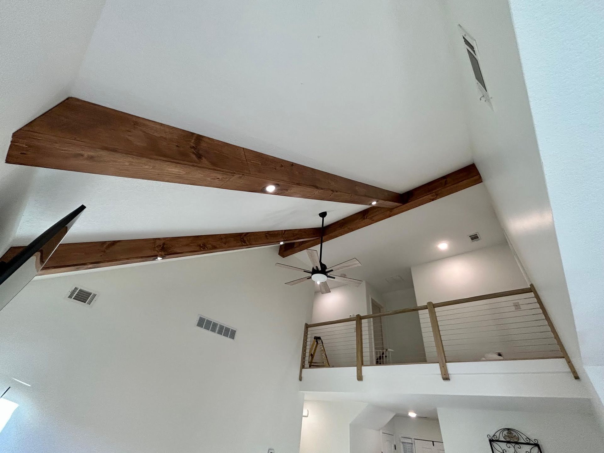 A living room with a ceiling fan and wooden beams.