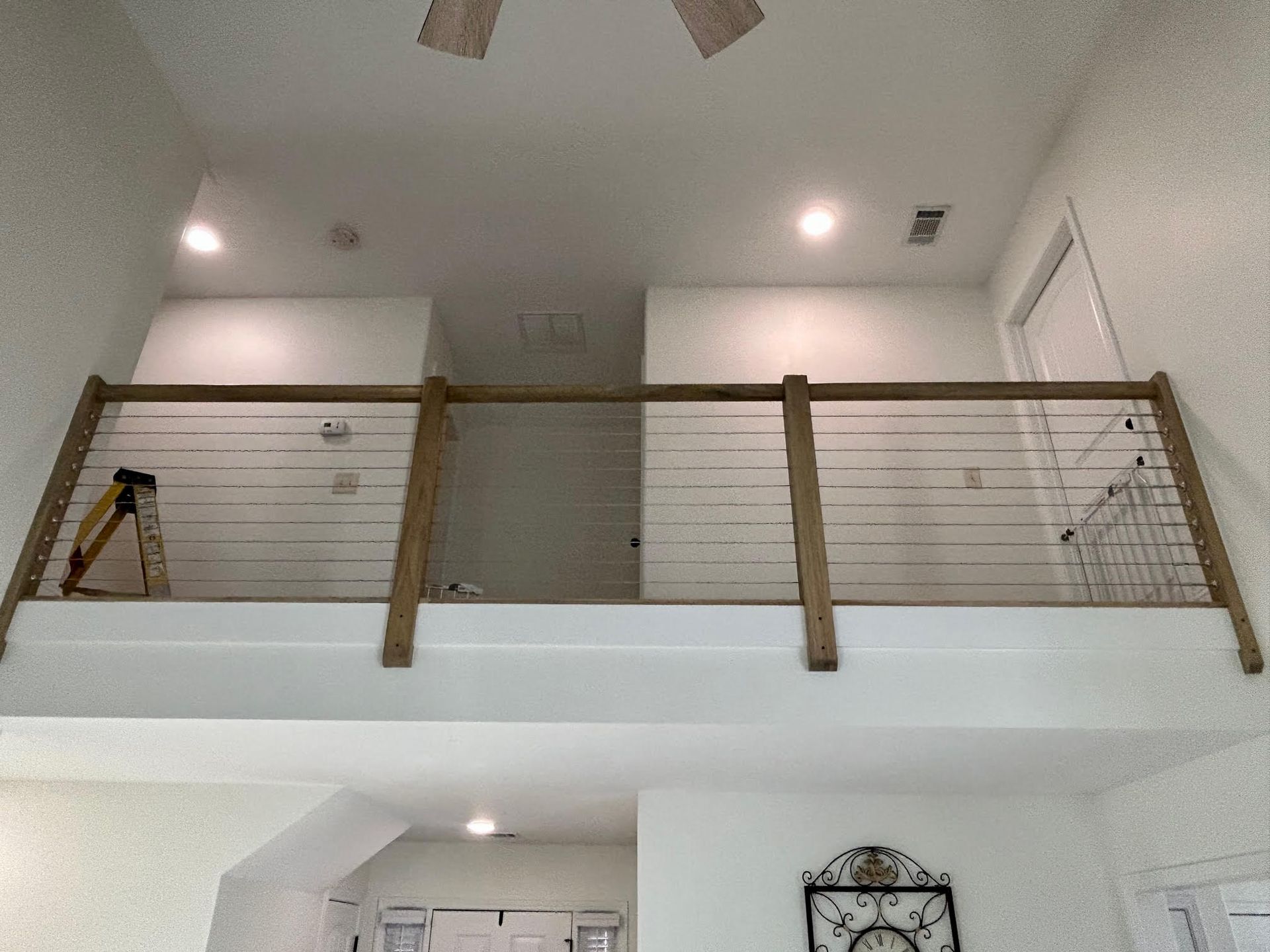 A balcony with a wooden railing and a ceiling fan in a house.
