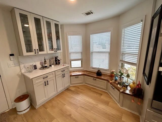 A kitchen with white cabinets and a window seat.