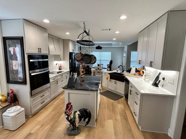 A kitchen with white cabinets and a black counter top.