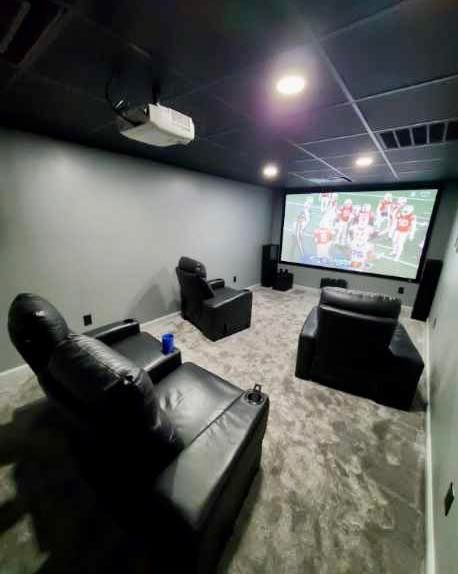 A home theater with a large screen , chairs , and a projector.