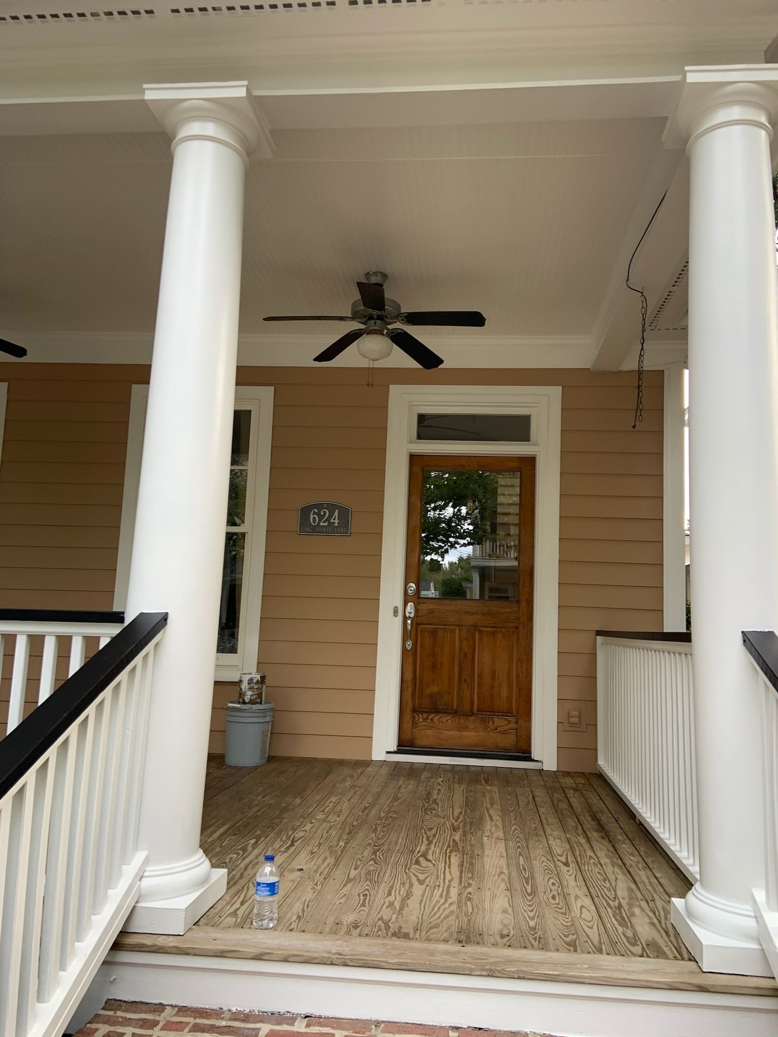 A porch with a wooden door and a ceiling fan