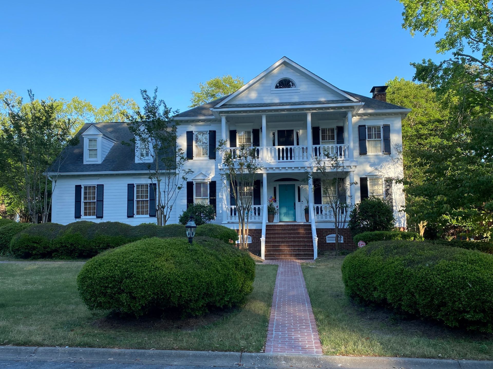 A large white house with black shutters and a blue door
