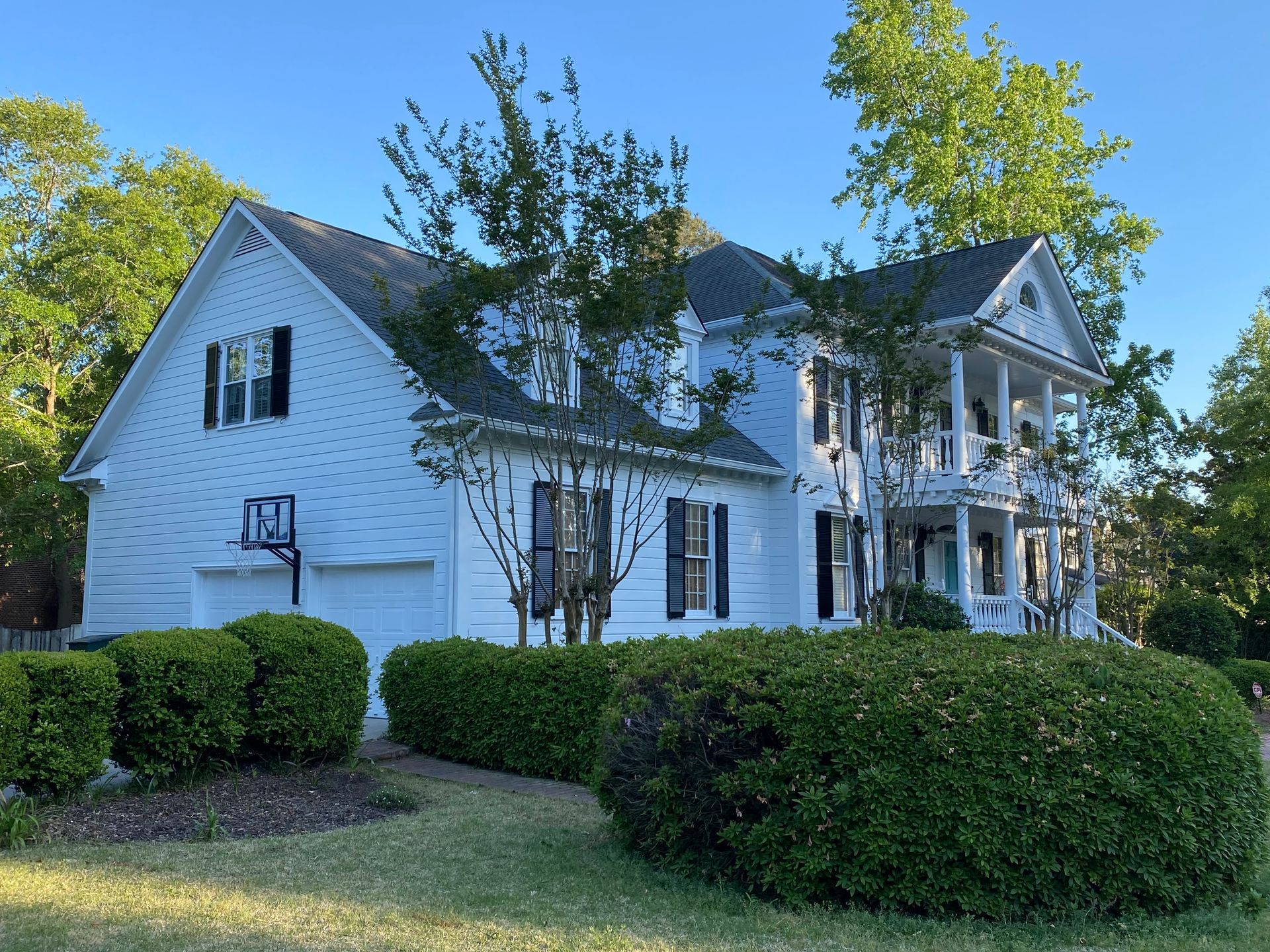 A large white house with a basketball hoop in front of it