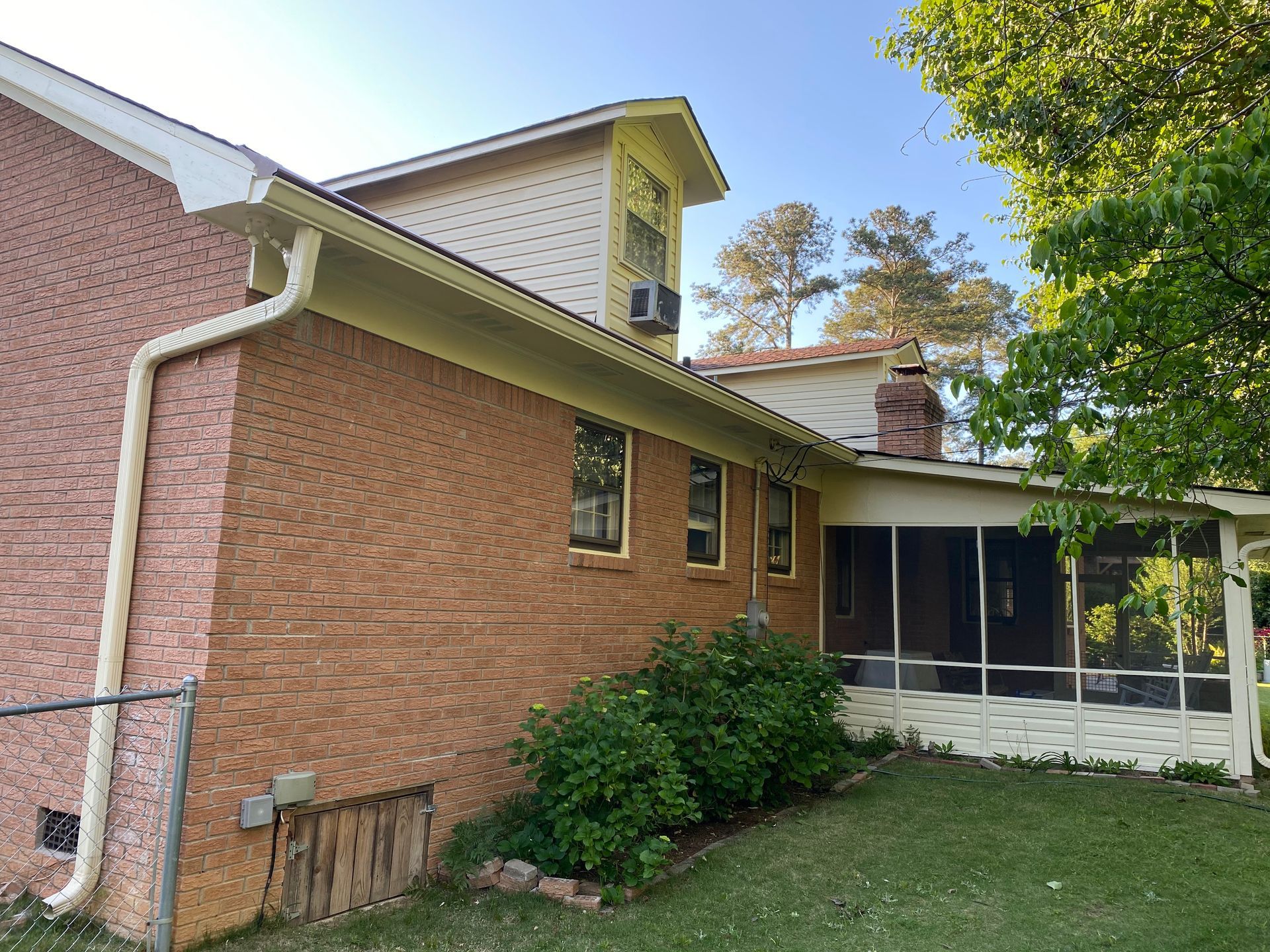 The back of a brick house with a screened in porch.