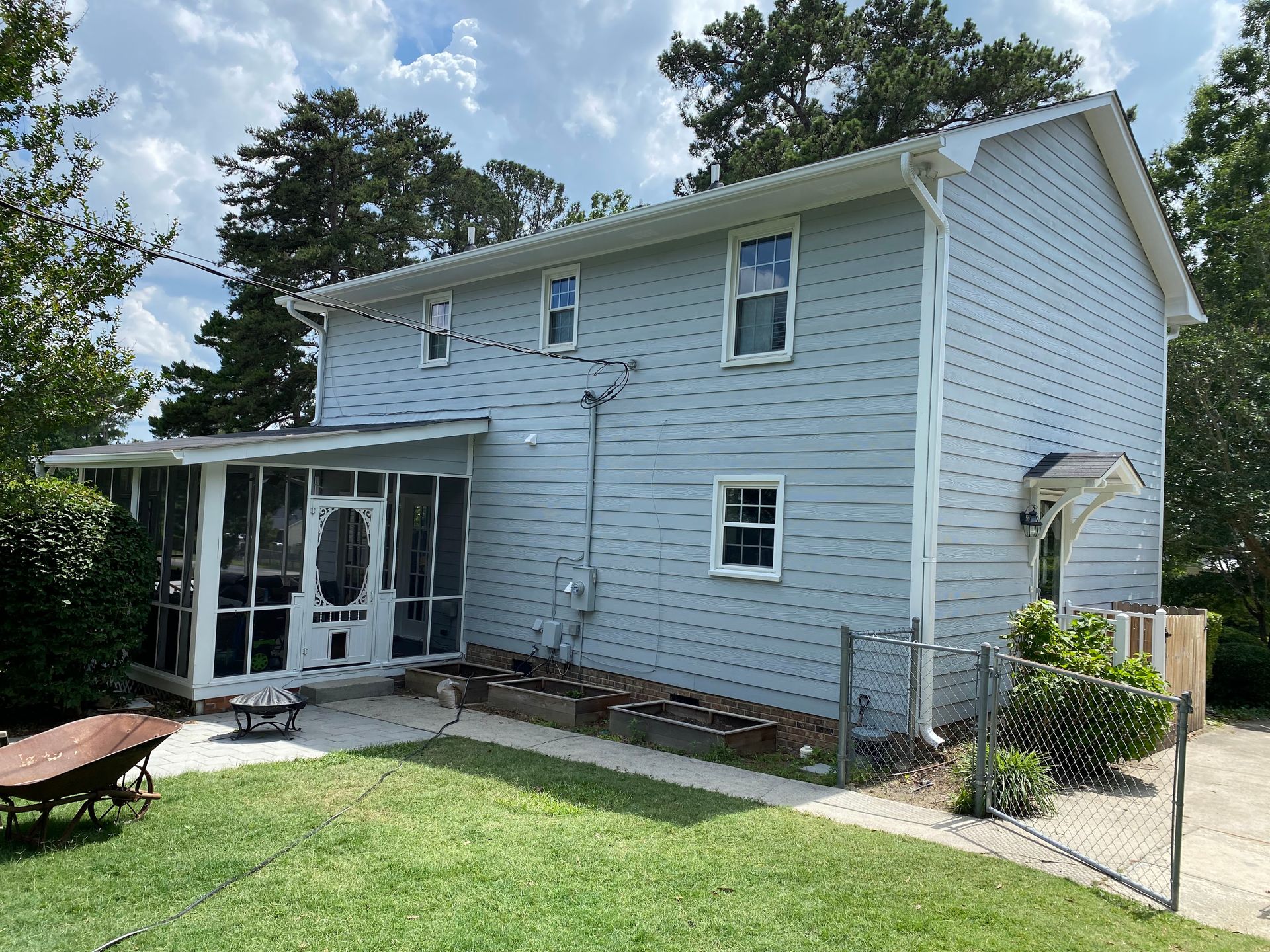 A white house with a screened in porch and a fence in front of it.