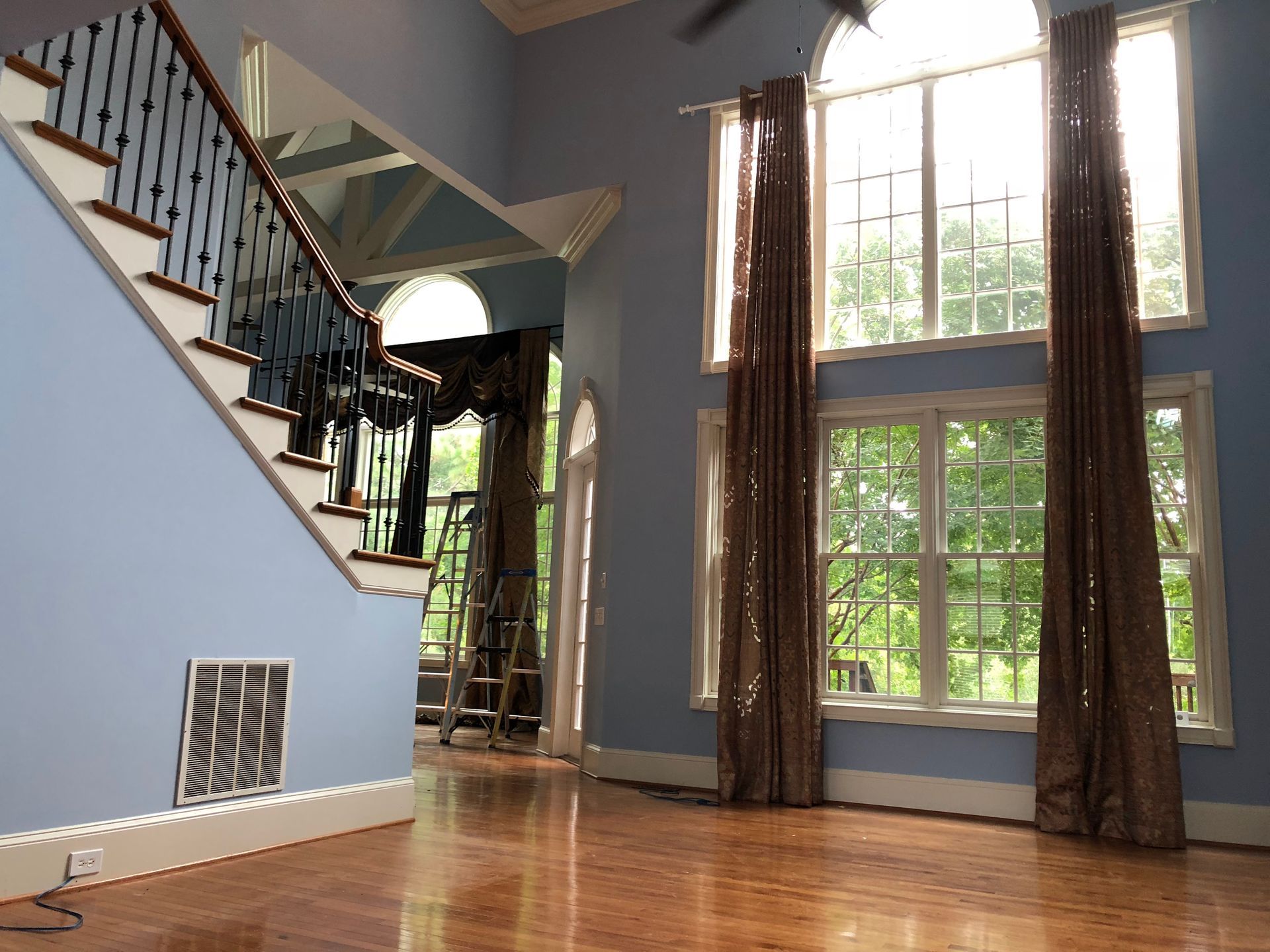An empty living room with stairs and lots of windows
