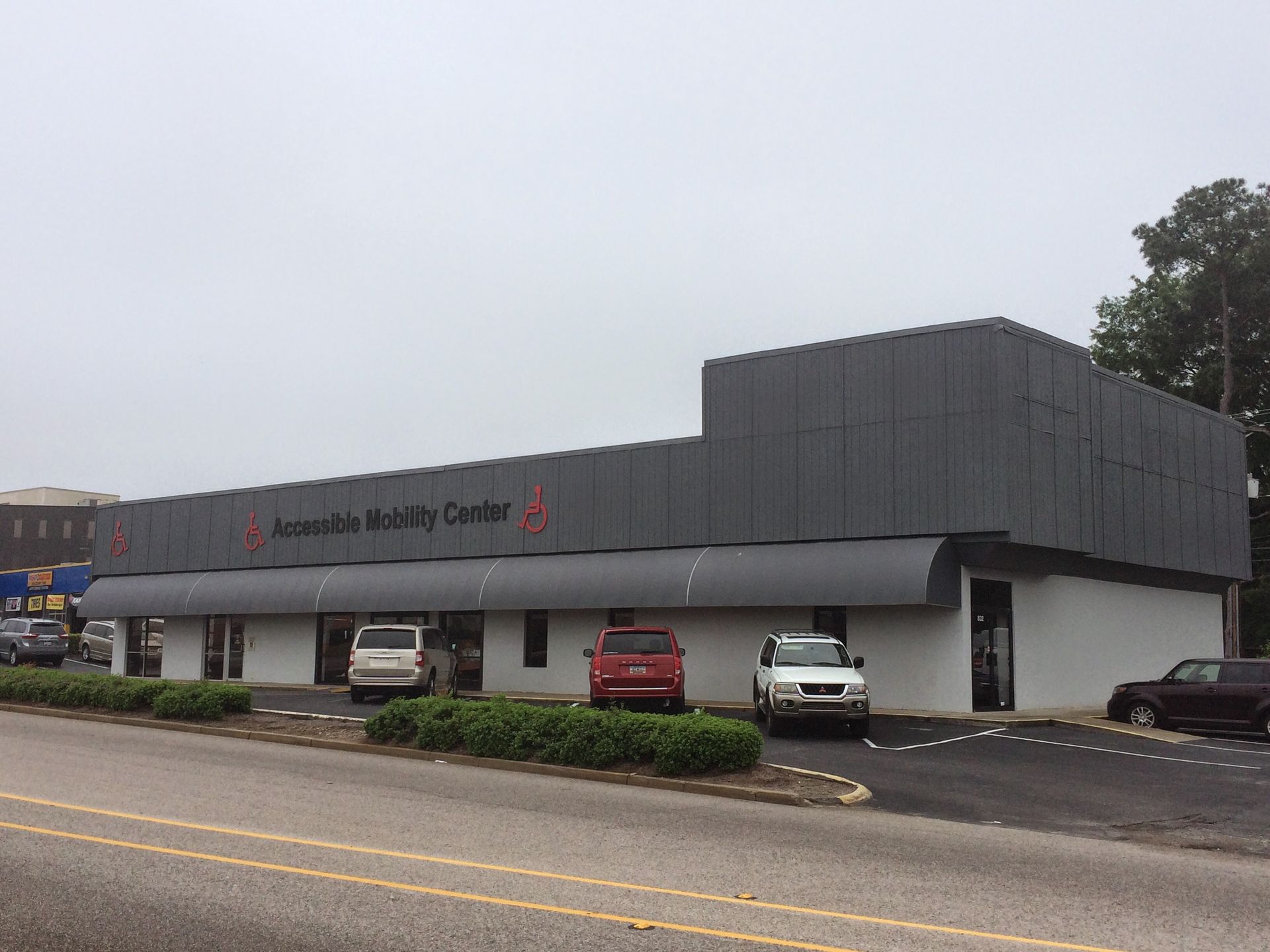 A white building with a gray awning and cars parked in front of it