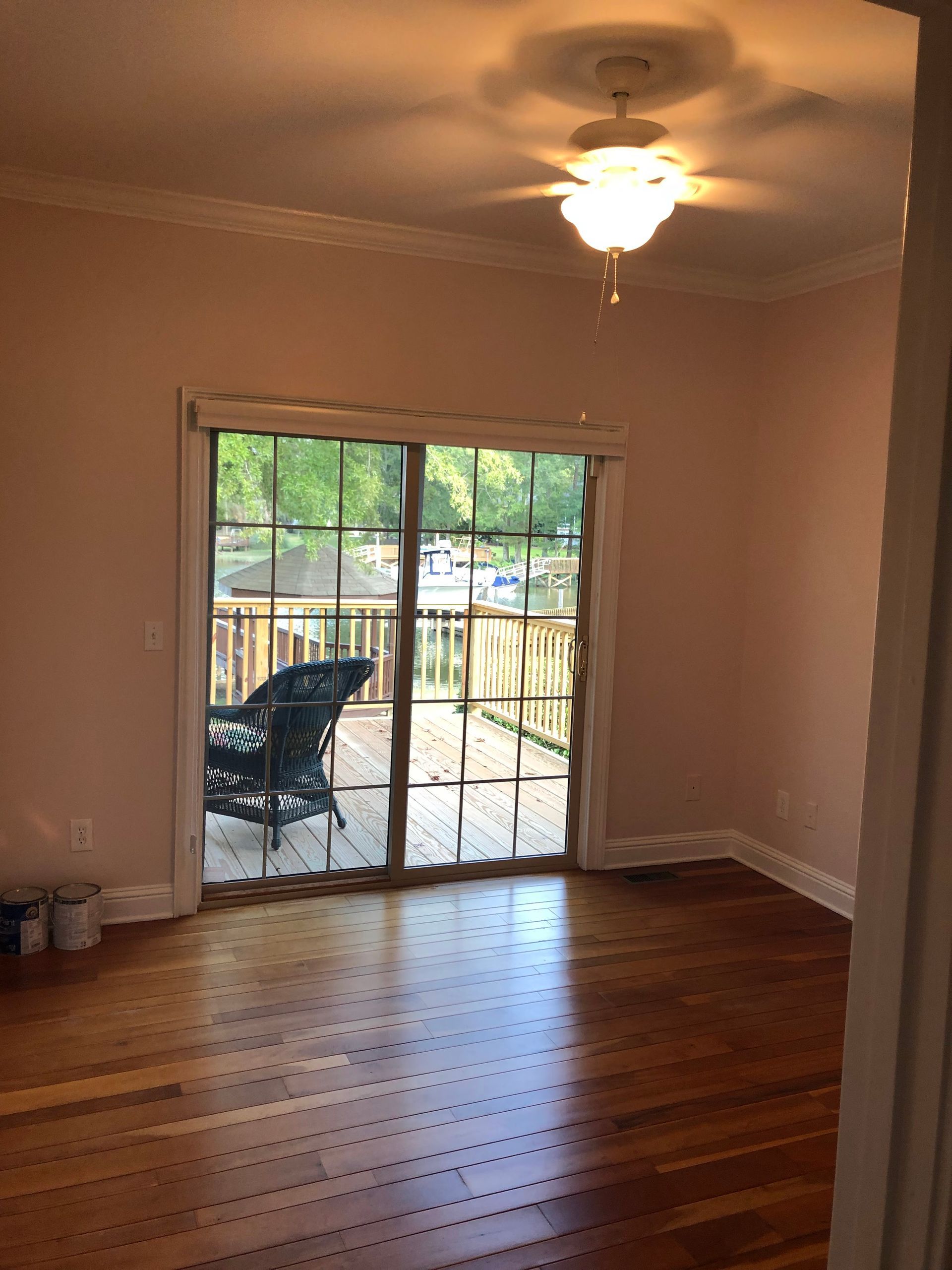 An empty room with a ceiling fan and sliding glass doors leading to a deck.