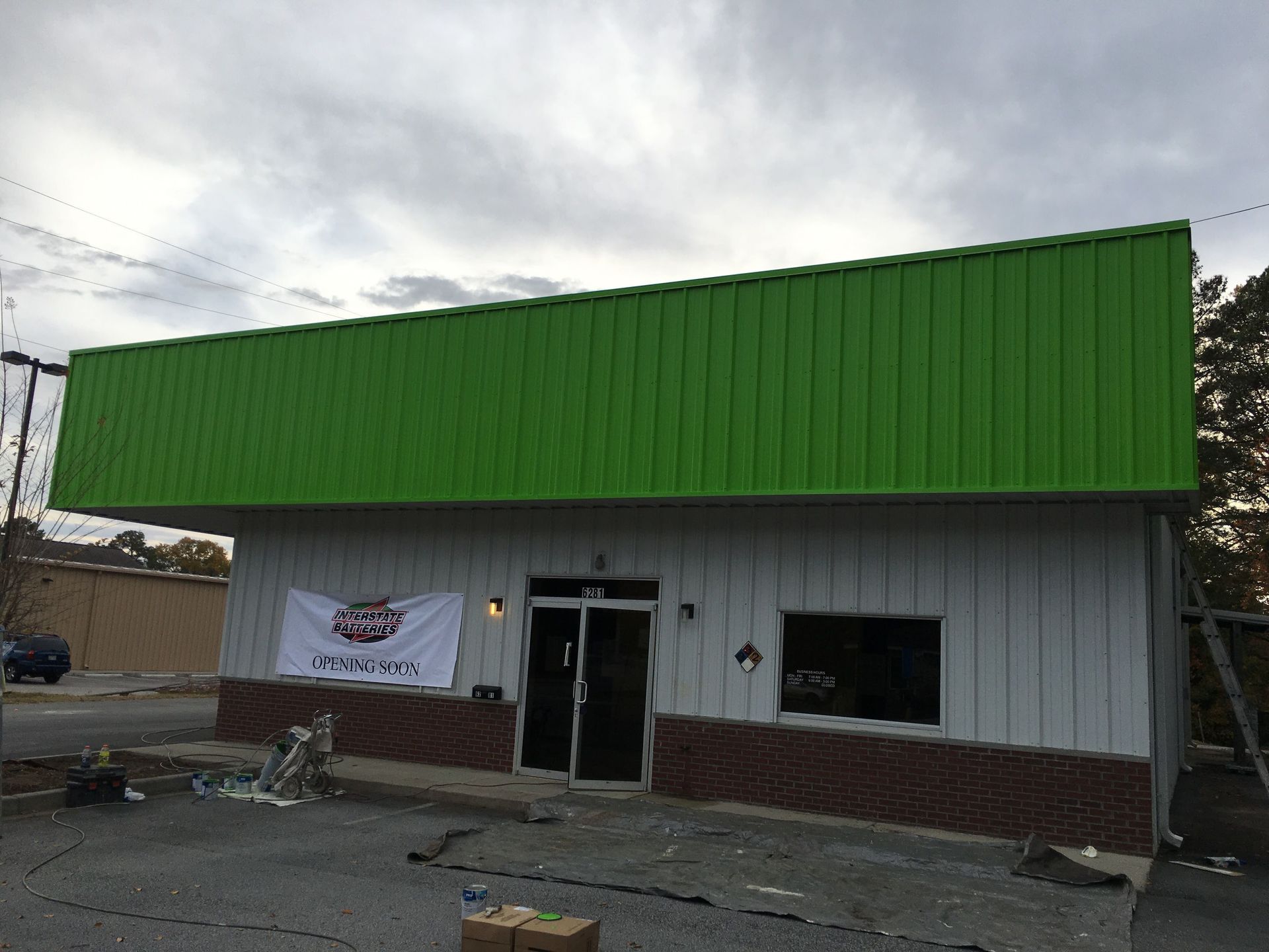 A white building with a green roof and a sign that says open