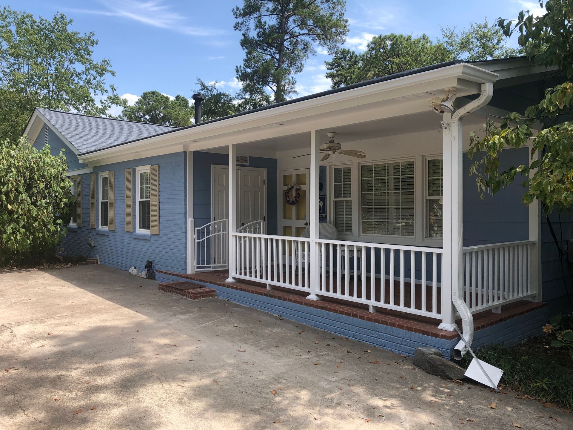 A blue house with a white porch and a white railing.