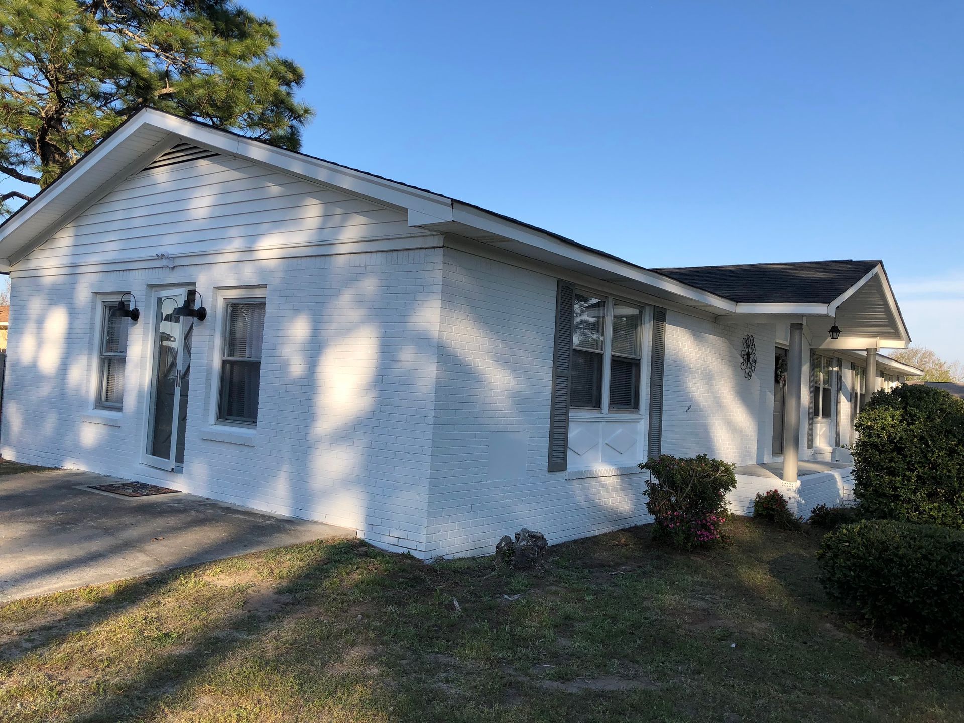 A white brick house with a black roof is for sale.