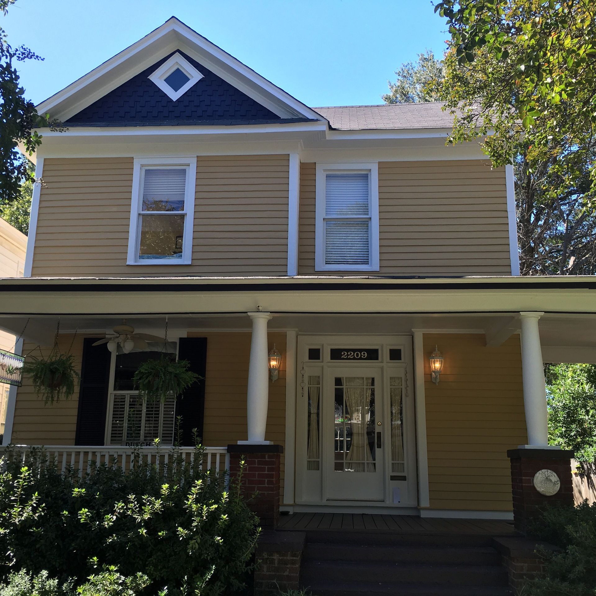 A yellow house with a black roof and a porch